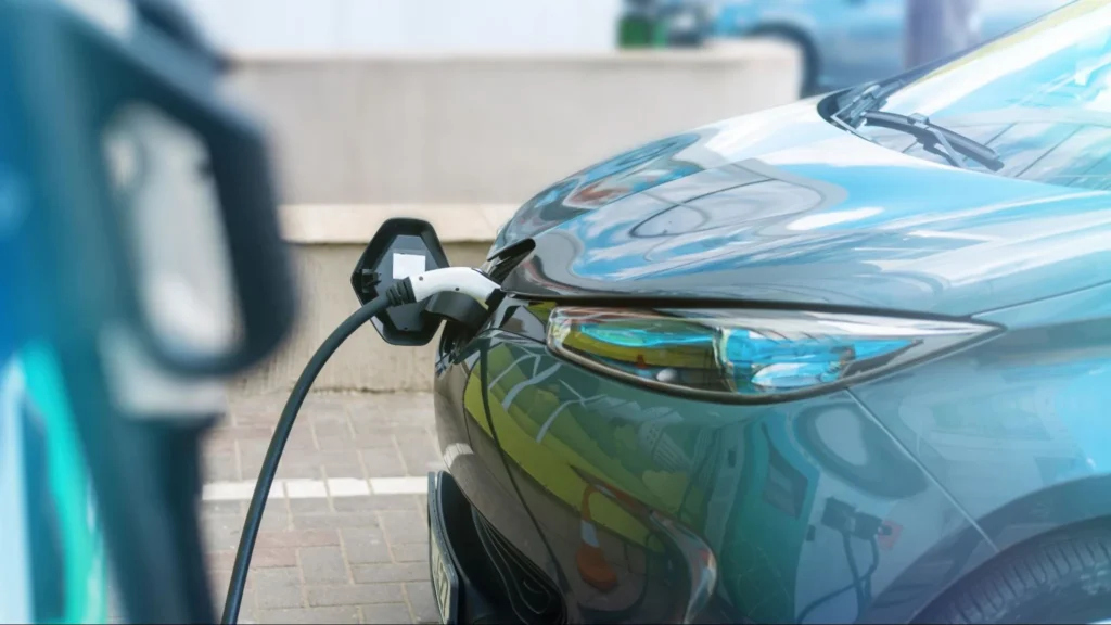 Side view of electric car charging at EV station with connected cable