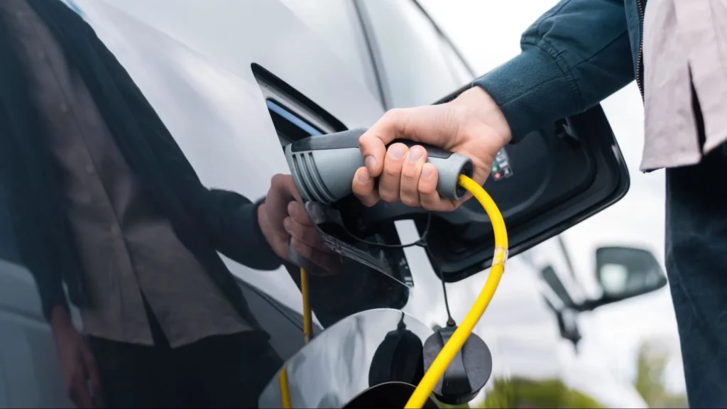 Hand plugging EV charger into electric car for safe battery charging
