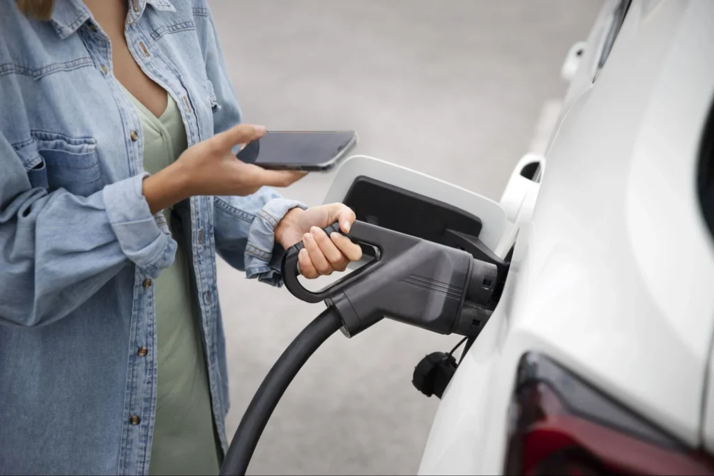 Person using smartphone while charging electric vehicle showing smart charging control