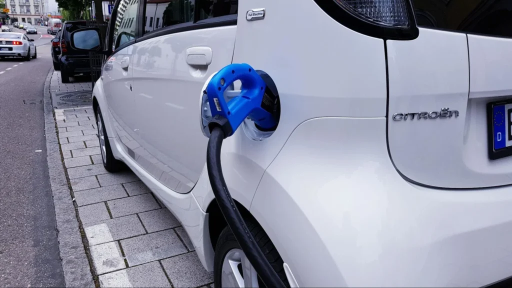 Electric car charging during daytime at a public charging station, representing peak electricity usage hours