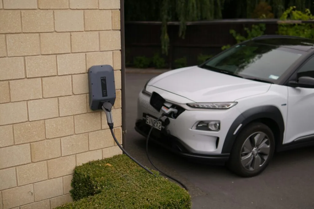 Electric vehicle charging at home using a wall-mounted EV charger in an outdoor residential setup
