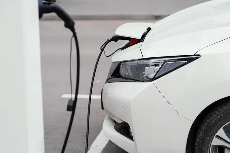 White electric car charging at an EV charging station