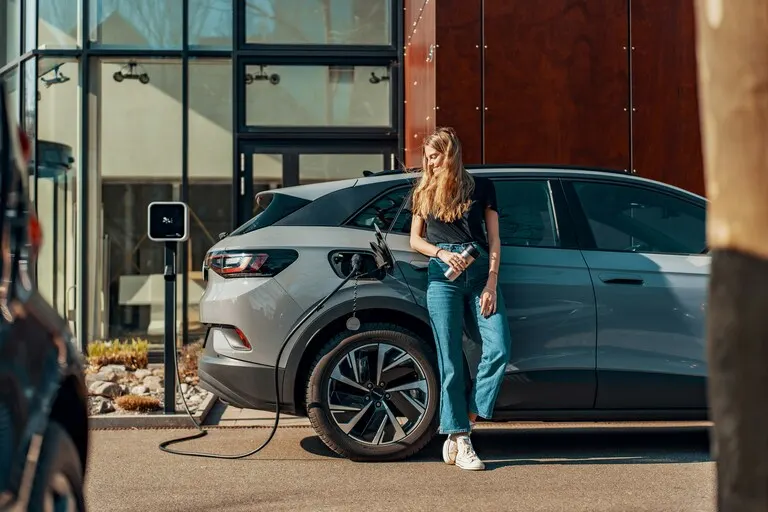 Woman charging an electric SUV at a public EV charging station